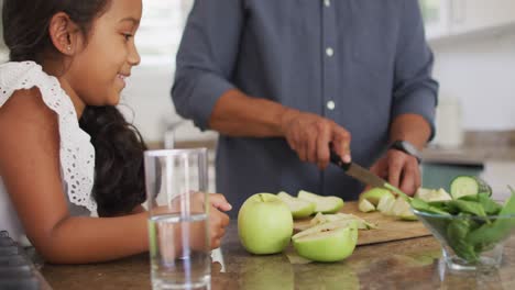 padre hispano enseñando a su hija sonriente a cocinar en la cocina