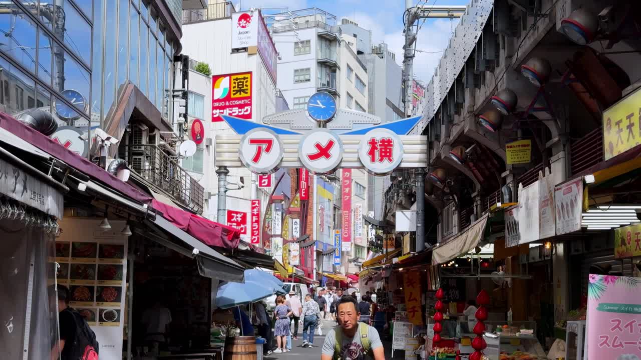Busy street market with signs, shops, and people walking under blue sky in Japan