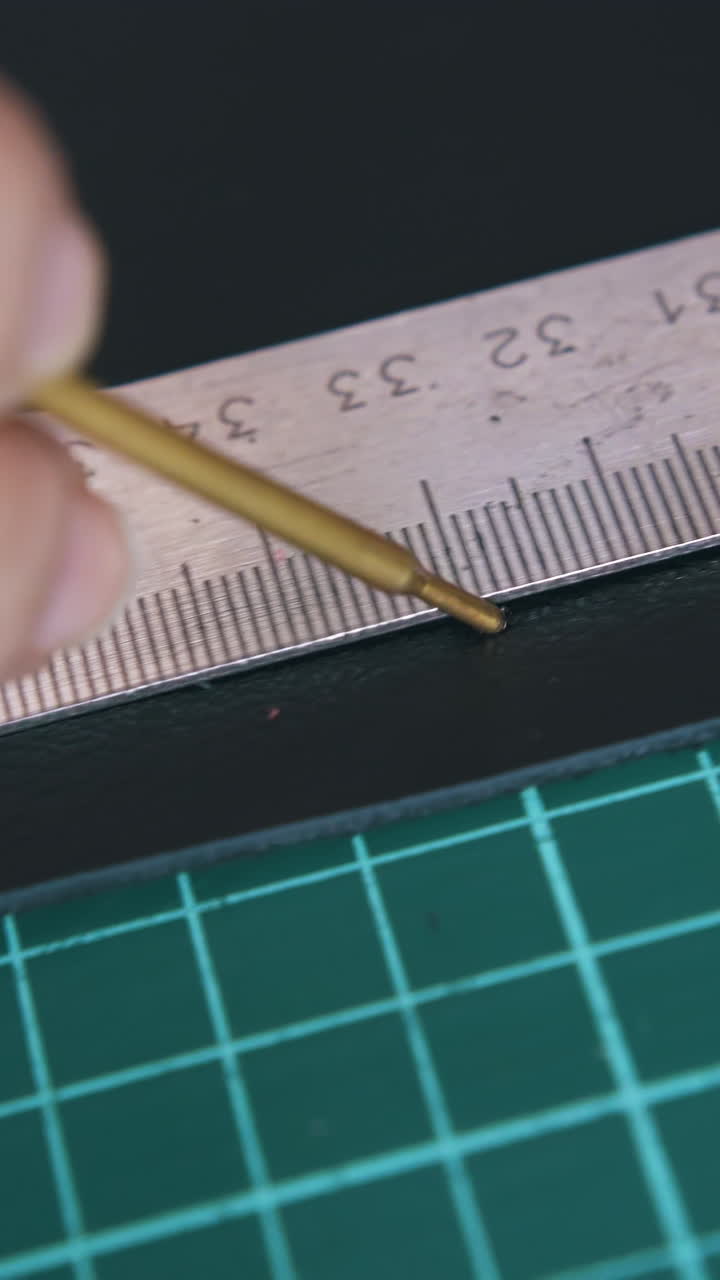 CU: Person draws white line on black leather fabric with special water soluble ink pen near ruler extreme close view