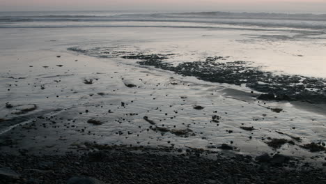 The-tide-comes-in-on-a-beach-during-sunset-in-Cardiff,-California,-near-San-Diego