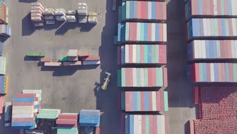 A-container-cargo-carrier-forklift-machine-moves-through-a-large-container-yard-while-many-truck-wait-to-be-loaded