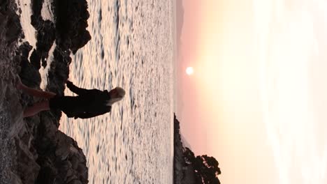 Attractive-blonde-girl-wearing-a-black-shirt-with-glasses-walks-towards-the-sunset-on-the-beach-in-Dubrovnik,-Croatia