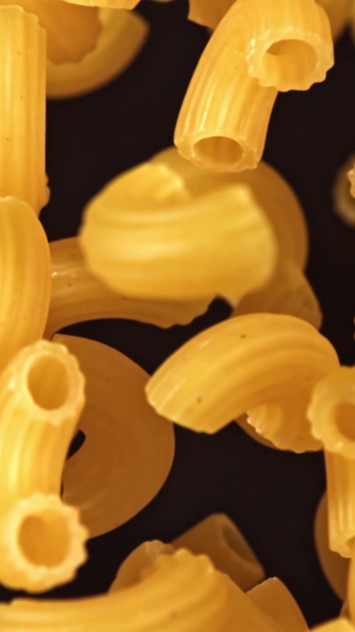 Primo piano di maccheroni a gomito crudi che cadono al rallentatore