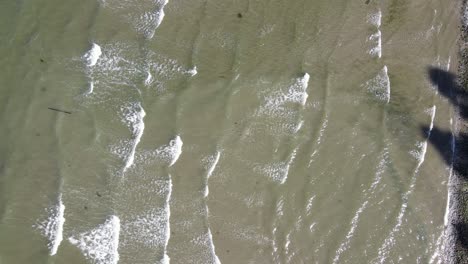 Vista-Aérea-De-ángulo-Alto-De-Olas-Largas-Rodando-En-Tierra-En-Una-Playa-Típica-En-El-Pnw-De-Columbia-Británica,-Canadá