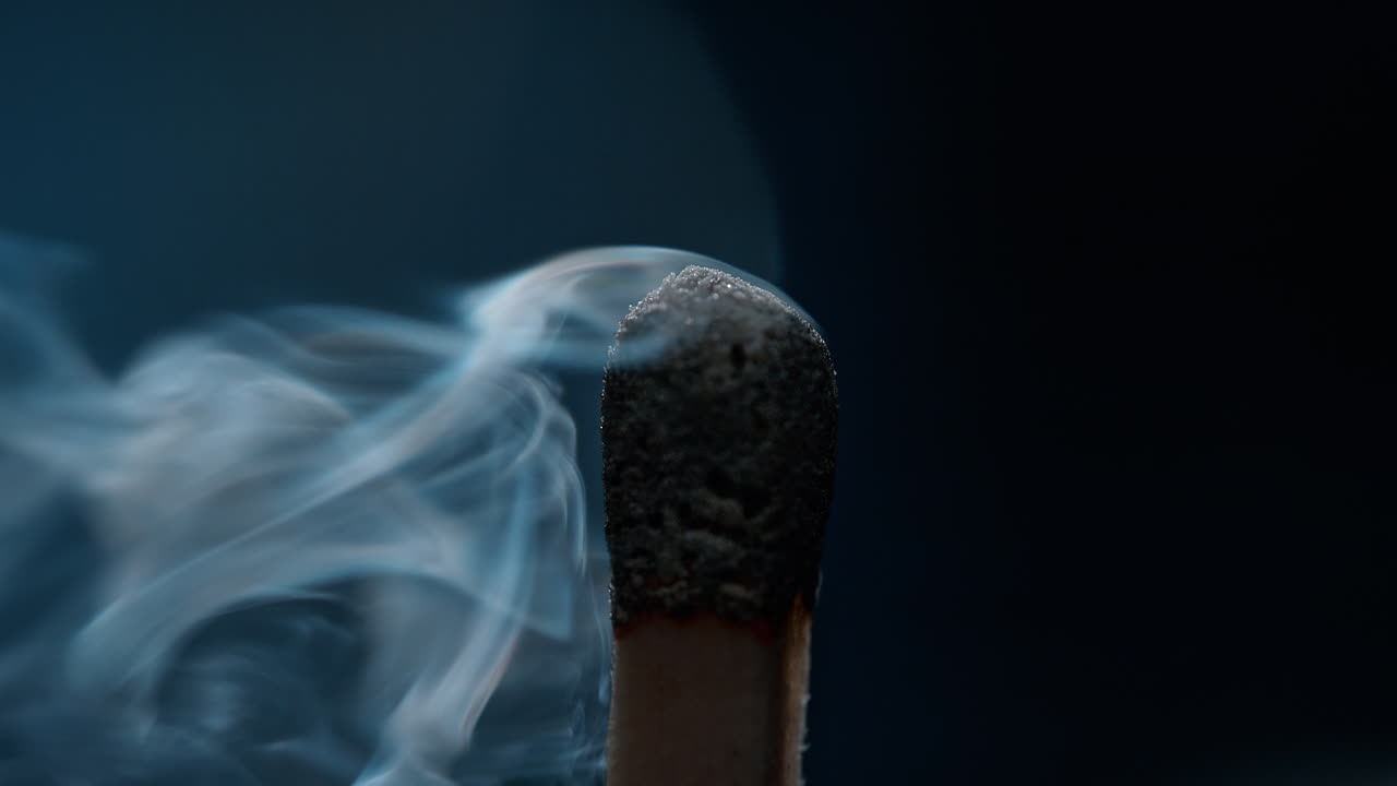 불타버린 황으로 불꽃을 피우고, 회색 연기가 파란색 배경에서 공중에 올라와 매크로와 느린 동작으로