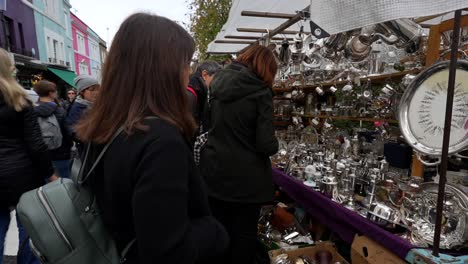 tourists browse a stall with vintage items at portobello road market in london