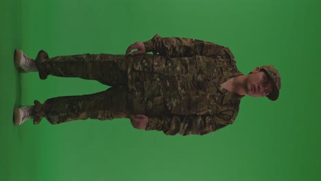 full body of distressed asian male soldier looking around and shaking his head being sad due to the war while standing on the green screen background