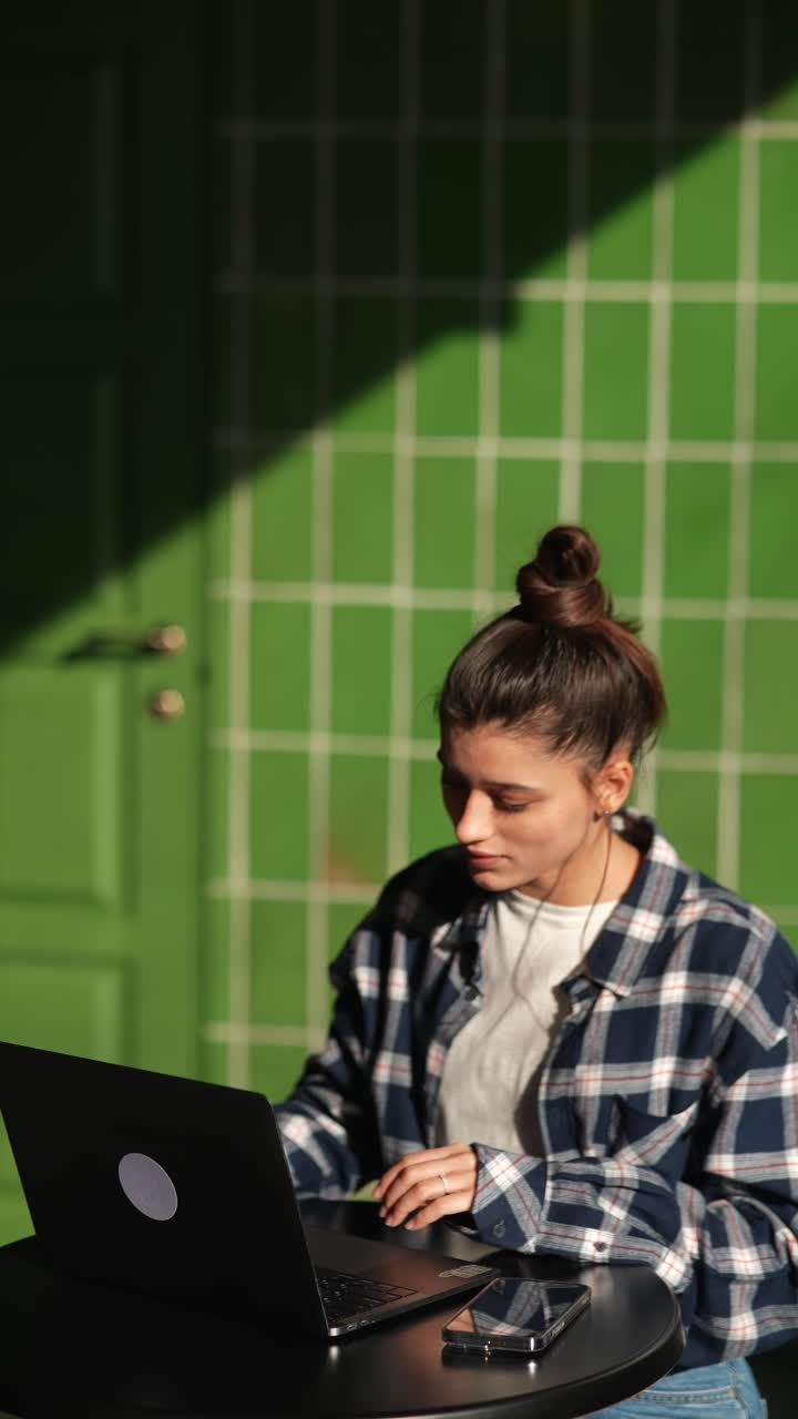 mujer joven trabajando en una computadora portátil en un café