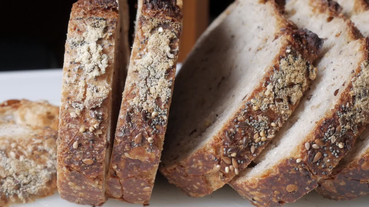 Sliced olive bread with seeds and a textured surface showing mold on some parts