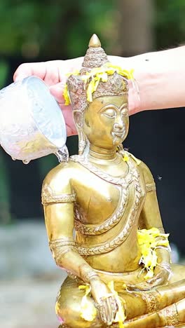 sequential pouring of water over a golden buddha statue