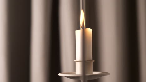 soft candle burns in front of drapes, close up bokeh slider shot