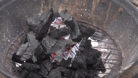 close-up of ashes flying off a coal pile on a grill in the daytime in 4k