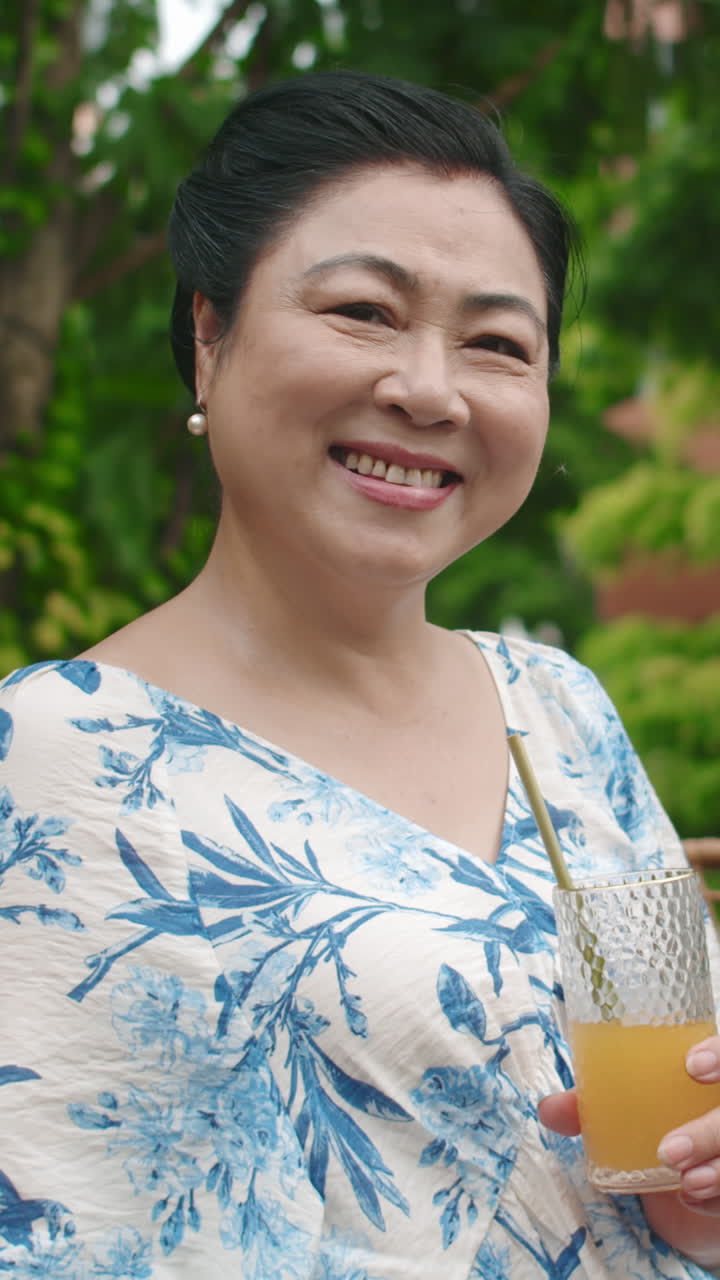 Portrait of Elderly Asian Woman Drinking Juice in Outdoor Cafe