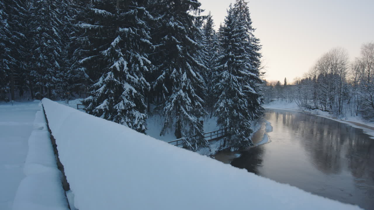Pan of river and forest from bridge in snowy wintertime Finland