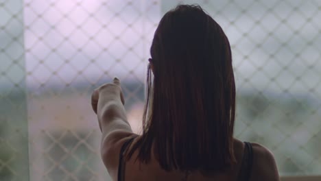 back of brunette woman's head, pointing outside apartment window in slow motion