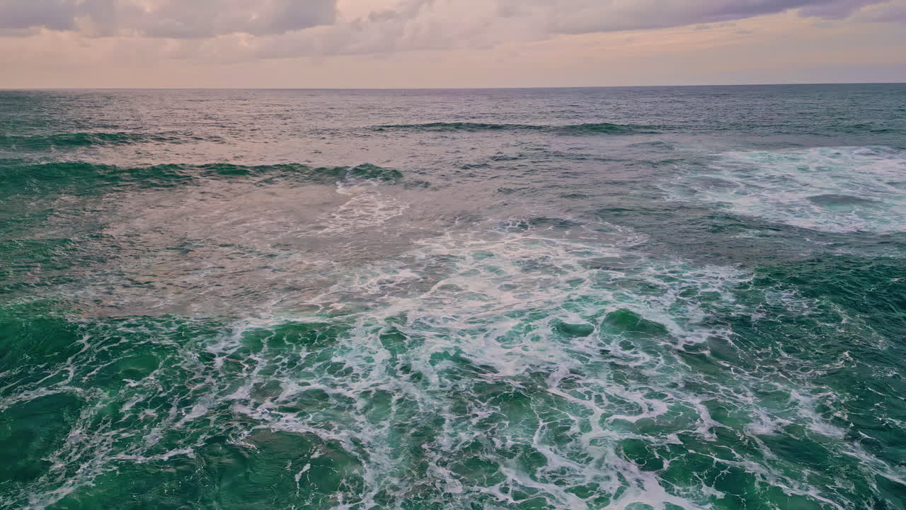 Drammatico paesaggio marino serale, vista aerea. L'acqua del mare che si increspa creando schiuma bianca.