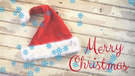 Animation-of-merry-christmas-text-over-santa-hat-and-snow-falling