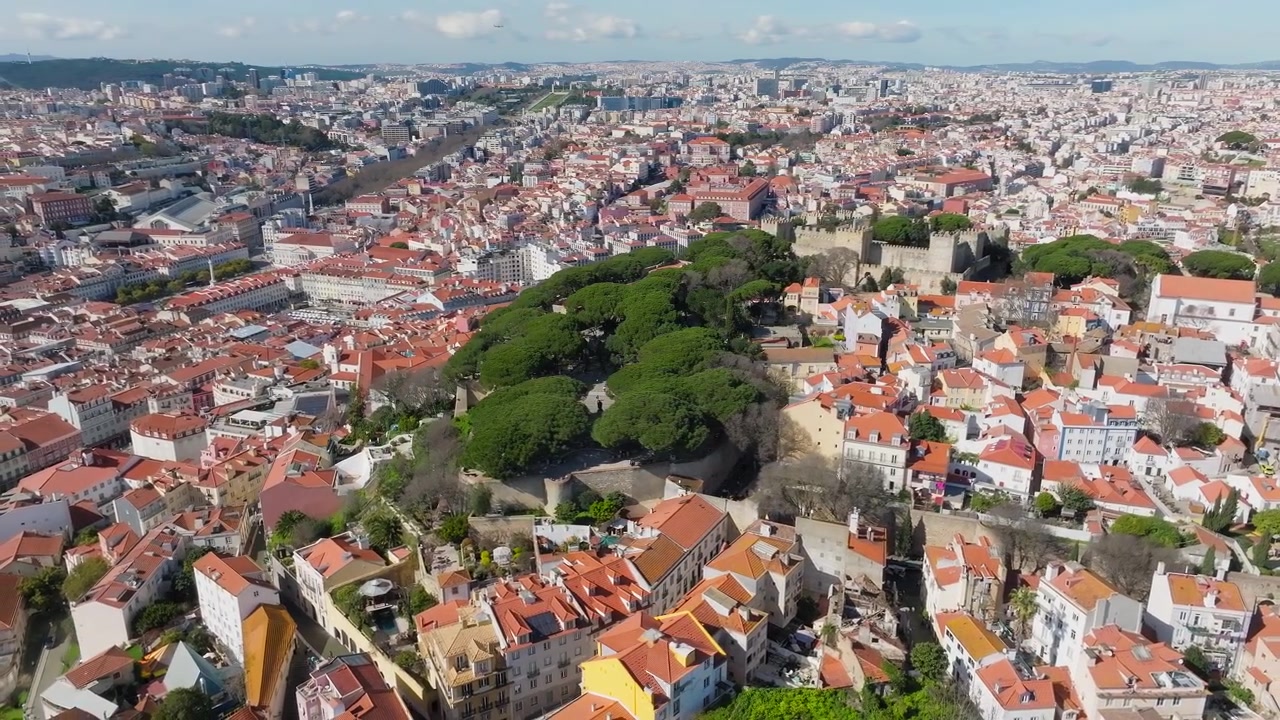 Pomalý panoramatický záběr dronem na Castelo de Sao Jorge v Lisabonu v poledne. Jasný slunečný den, čistá modrá obloha. Historický hrad na kopci. Portugalsko