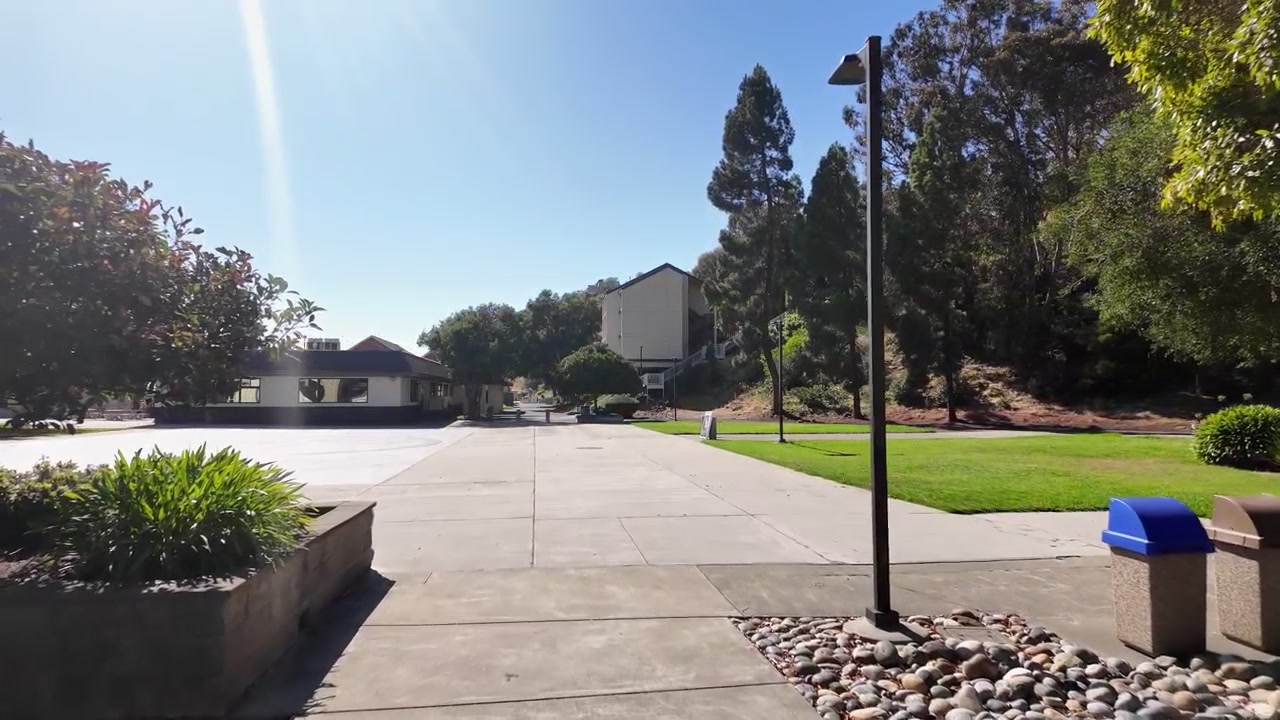 Point of view shot moving forward along a concrete path through the California State University Maritime Academy campus on a sunny day with a clear blue sky in Vallejo, California