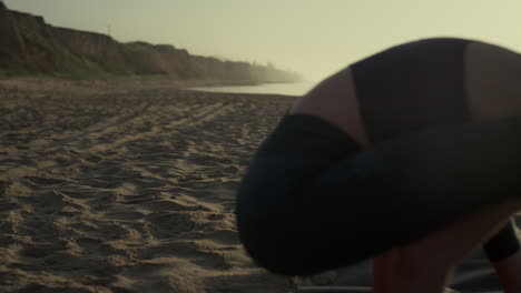 girl standing yoga crane pose on beach closeup. woman practicing bakasana.