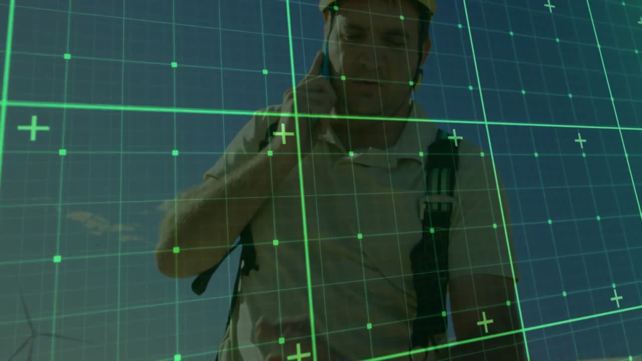Griglia verde che rivela un tecnico di parco eolico che solleva lo smartphone e tocca un tablet sul petto per i controlli.