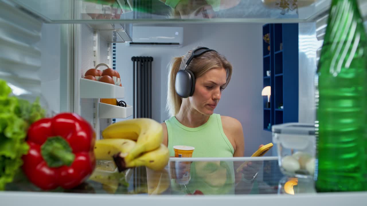 mujer mirando el teléfono dentro de un refrigerador