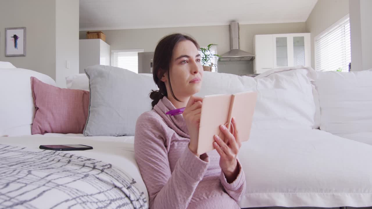 바닥에 앉아서 메모를 하는 행복한 백인 여성