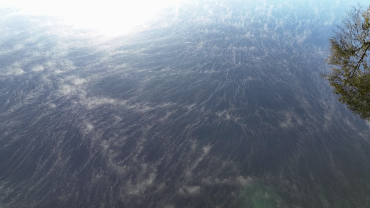 Morning mist forms swirling patterns across the calm reflective lake surface