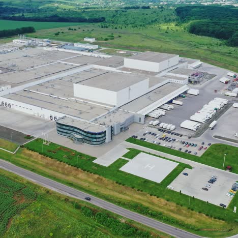 Industrial zone in the countryside. Huge territory of innovative plant surrounded by beautiful green nature. Aerial view.