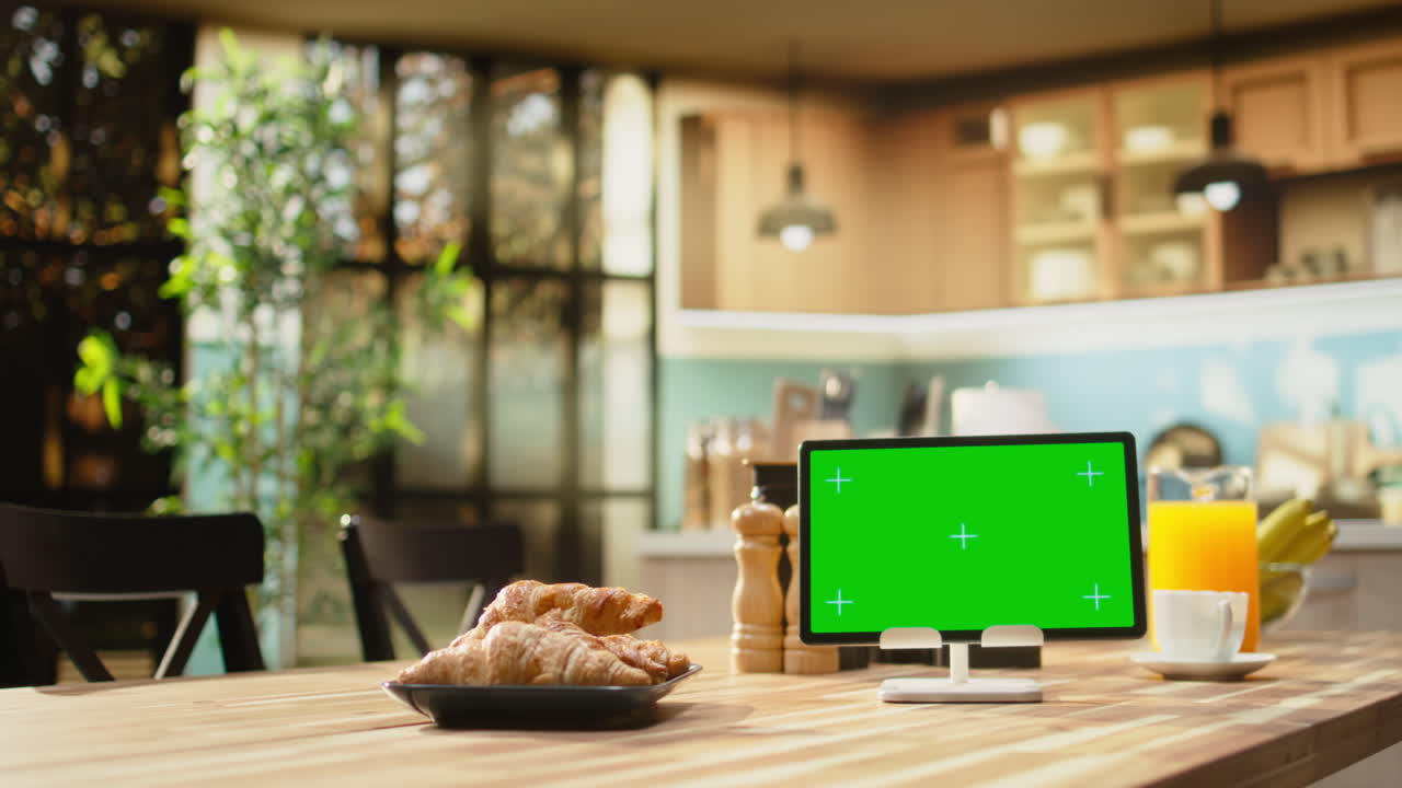 Schermo chroma key su tablet in luminosa e spaziosa cucina con tavolo per la colazione