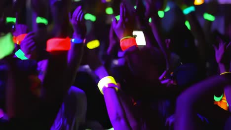 fans waving hands with colorful glow sticks at a lively concert, immersing in the excitement of live music and creating a vibrant, energetic atmosphere filled with joy and celebration