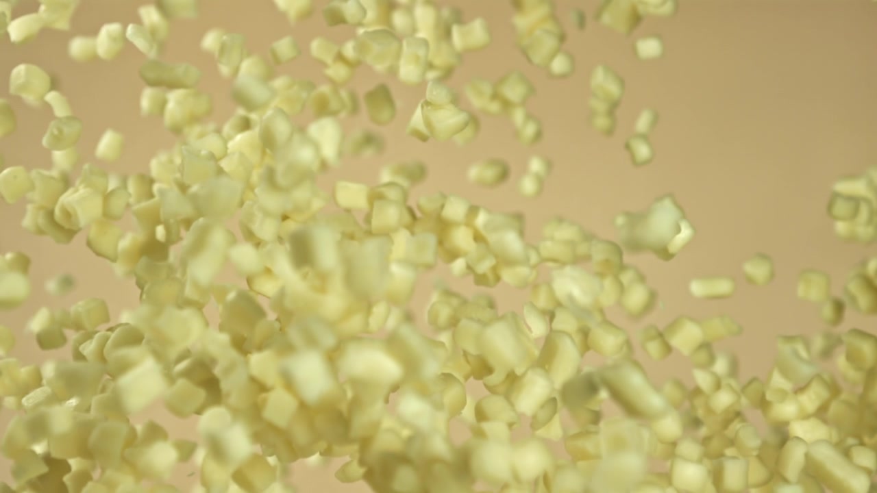 Piccole zollette di zucchero che cadono al rallentatore su sfondo beige