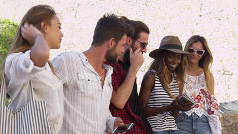 Five-friends-on-vacation-in-Ibiza-looking-at-a-guidebook,-shot-on-R3D