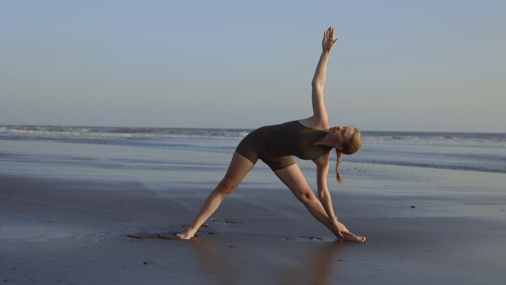 Donna che pratica lo yoga sulla spiaggia