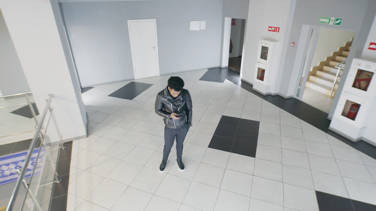 People Engaged with Smartphones in a Modern Office Building Hallway
