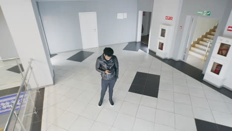 people engaged with smartphones in a modern office building hallway