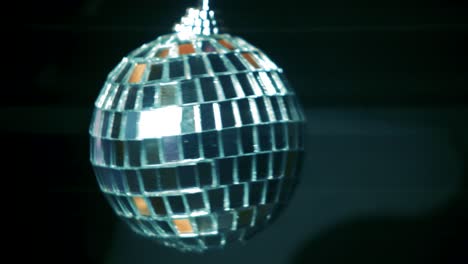 Small-rotating-disco-ball-with-reflected-moving-rays,-Anamorphic-lens-flare,-close-up-shot,-abstract-background-concept