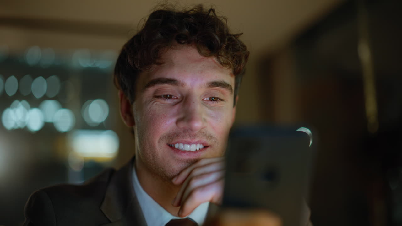 Uomo d'affari che guarda i social media sul cellulare in un ufficio buio, primo piano