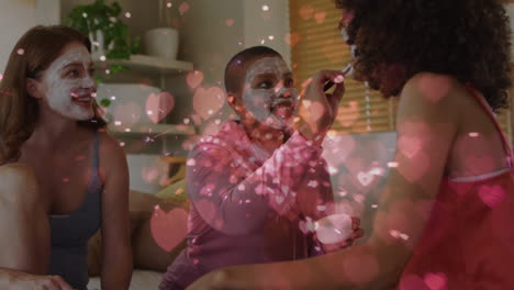 animation of hearts over diverse group of female friends with beauty face masks