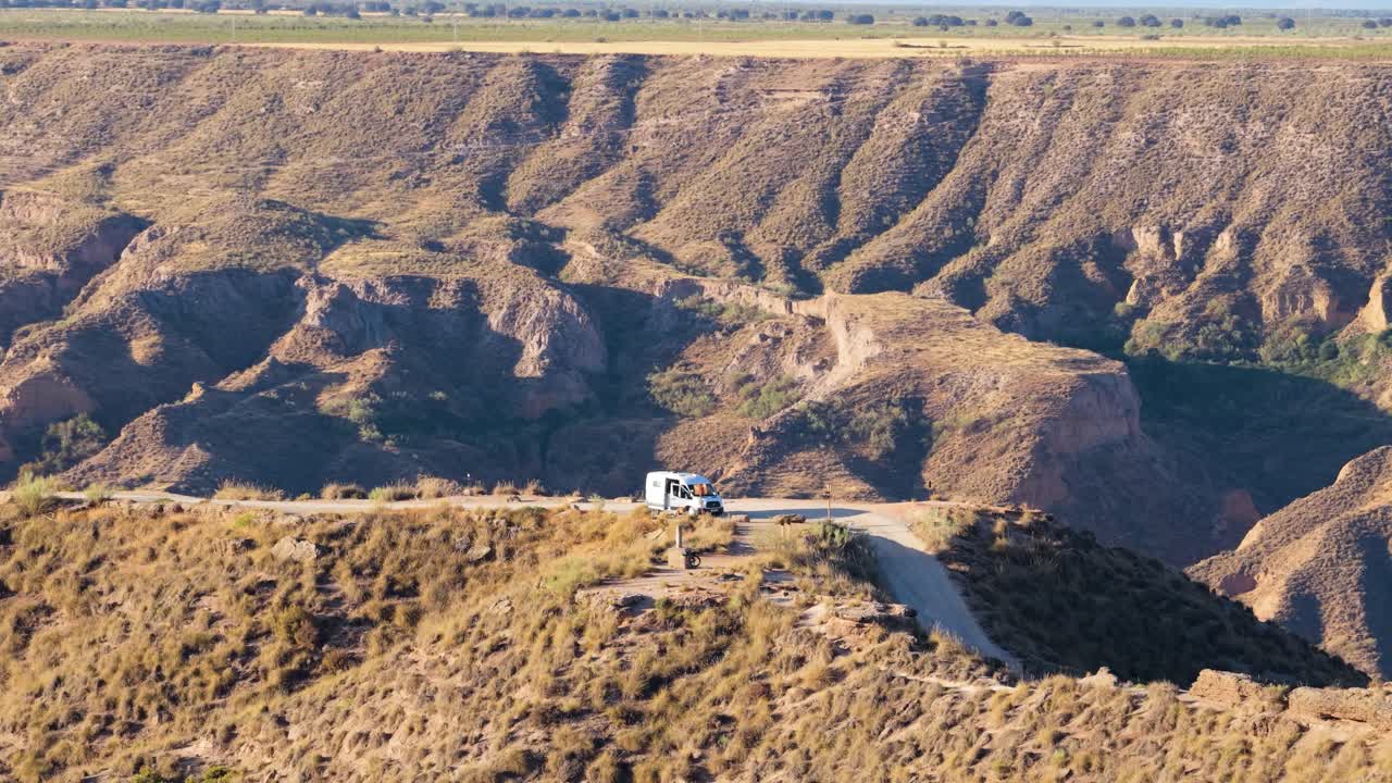 Furgoneta camper estacionada en un camino de tierra con vistas a un vasto paisaje de cañón