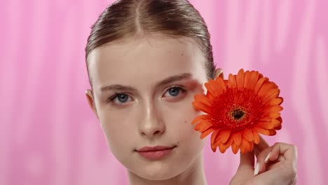young woman with bright orange flower on vibrant background a serene moment of a woman enjoying the scent of a vibrant orange flower eyes closed in relaxation
