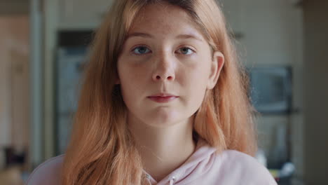 retrato de una hermosa adolescente de cabeza roja con pecas en la cocina en casa buscando una expresión seria
