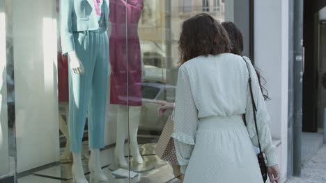 hermosa dama llamando a un amigo y mostrando ropa en la ventana de la tienda