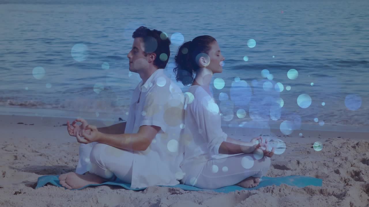 Sahilde mavi bir mat üzerinde meditasyon yapan çift, sağlıklı yaşam için doğru kişinin etrafında bokeh etkisi yoğunlaşıyor