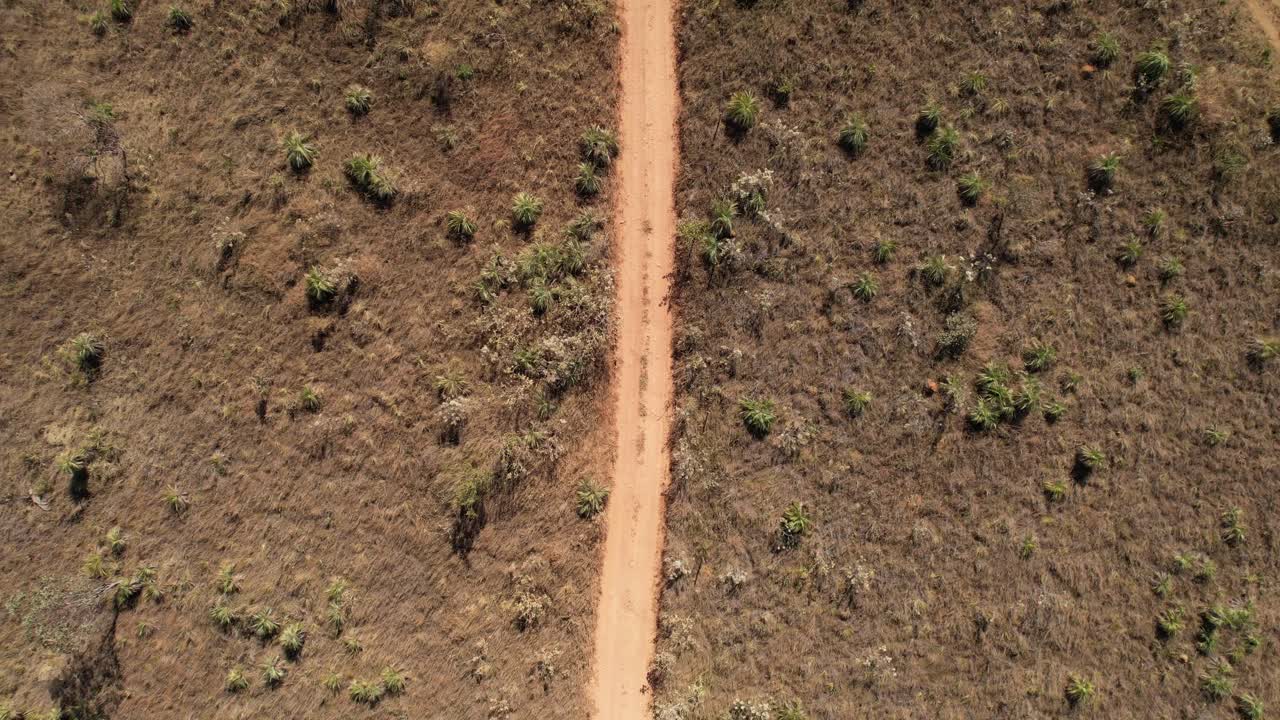 drone orbital view of a moving car raising dust on a dirt road in Chapada dos Veadeiros, Goi&aacute;s, Brazil