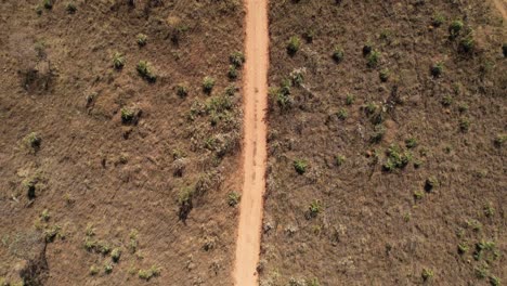 vista orbital de un avión no tripulado de un automóvil en movimiento levantando polvo en un camino de tierra en chapada dos veadeiros, goiás, brasil