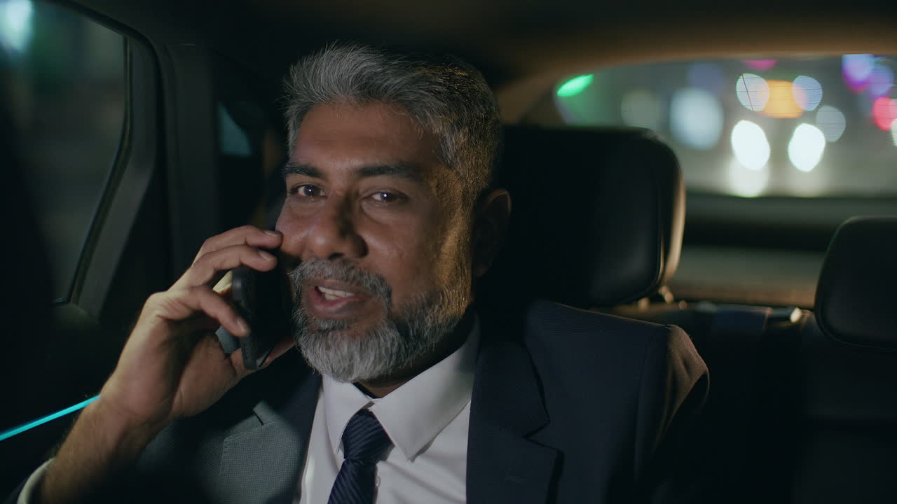 Mature Businessman Having Phone Talk in Car during Ride at Night