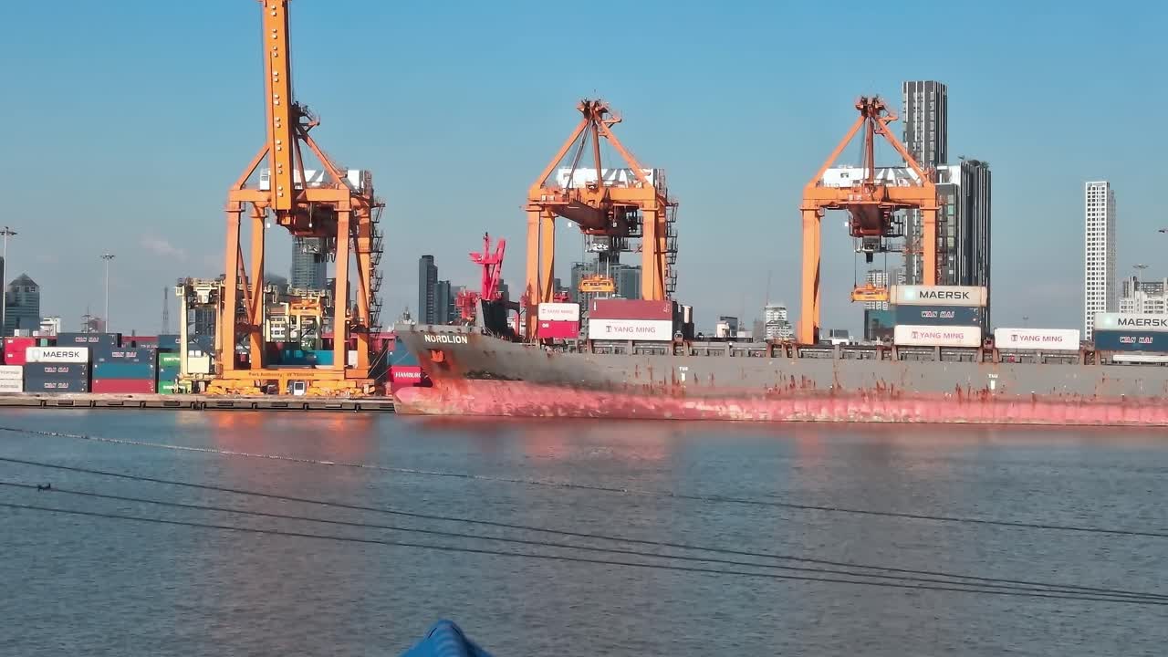 Cargo ship at port in Bangkok with city skyline in the background