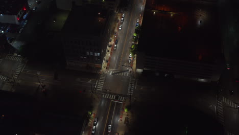 Aerial-tilt-down-footage-of-cars-driving-through-intersection-at-night.-Streets-lit-by-street-lights.-Dallas,-Texas,-US