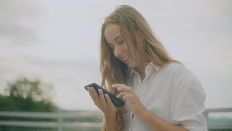 Mujer-Sonriente-Enviando-Mensajes-De-Texto-Al-Teléfono-Inteligente